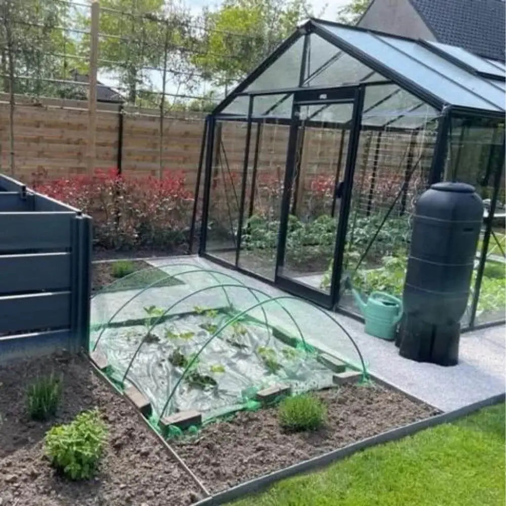 Serre de jardin en verre 11m² en situation réelle dans un jardin avec des accessoires